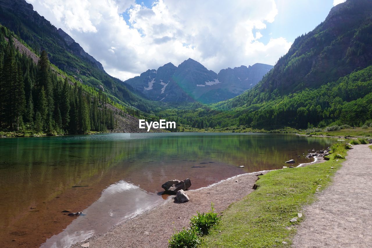 Scenic view of lake surrounded by mountains against cloud - sky