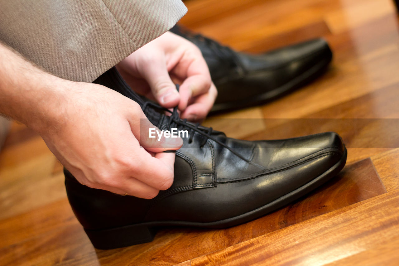 Midsection of man tying shoelace