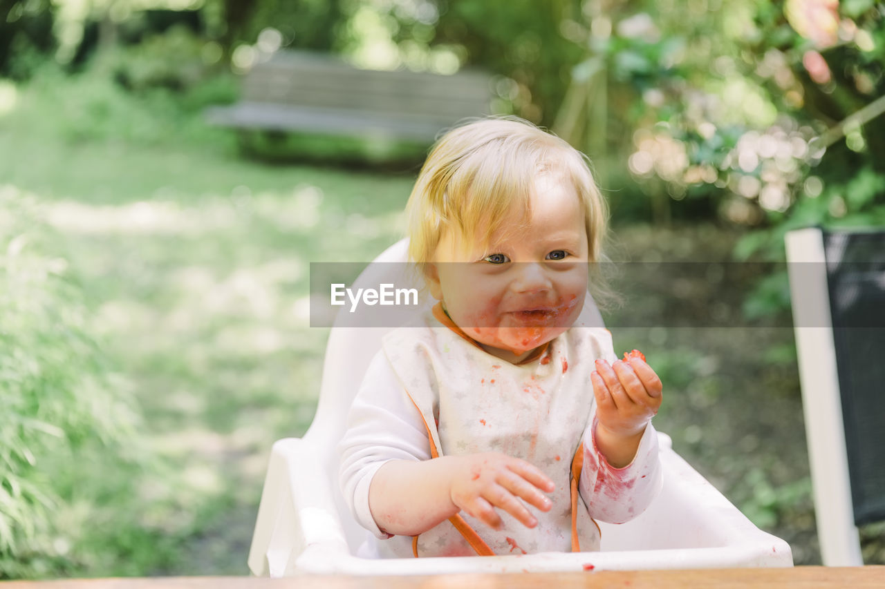 Cute girl eating while sitting outdoors