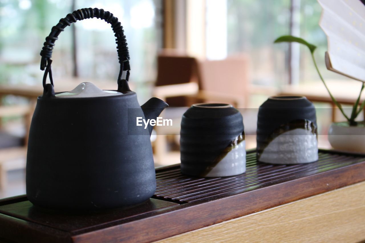 Close-up of kettle with cups on table in cafe