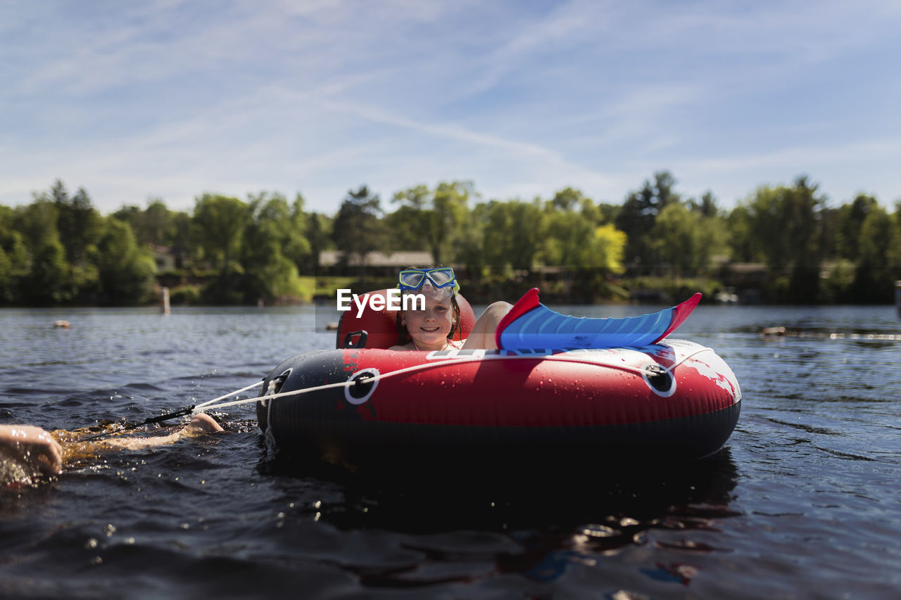 Portrait of girl in inflatable ring on river against sky