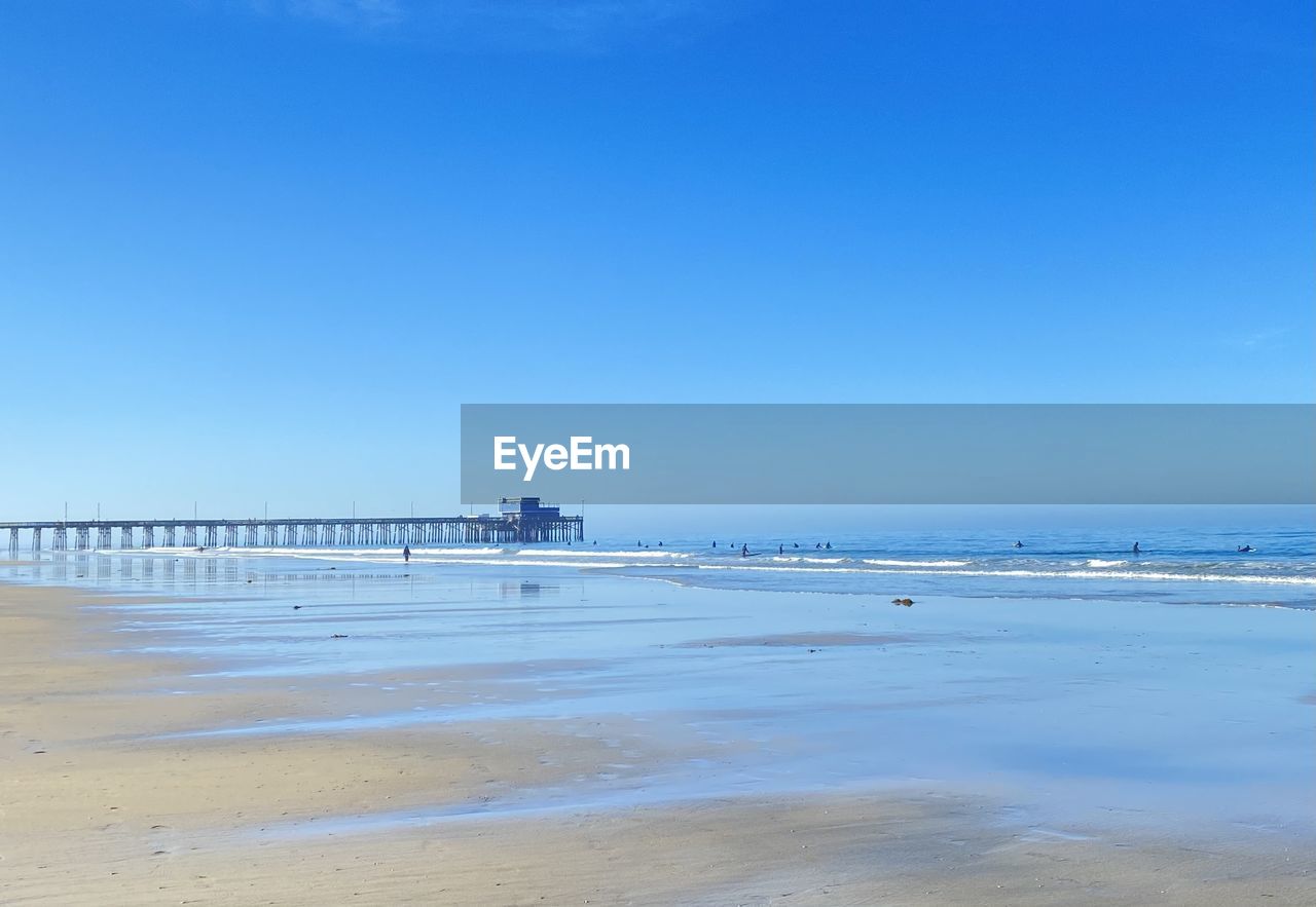 SCENIC VIEW OF BEACH AGAINST BLUE SKY