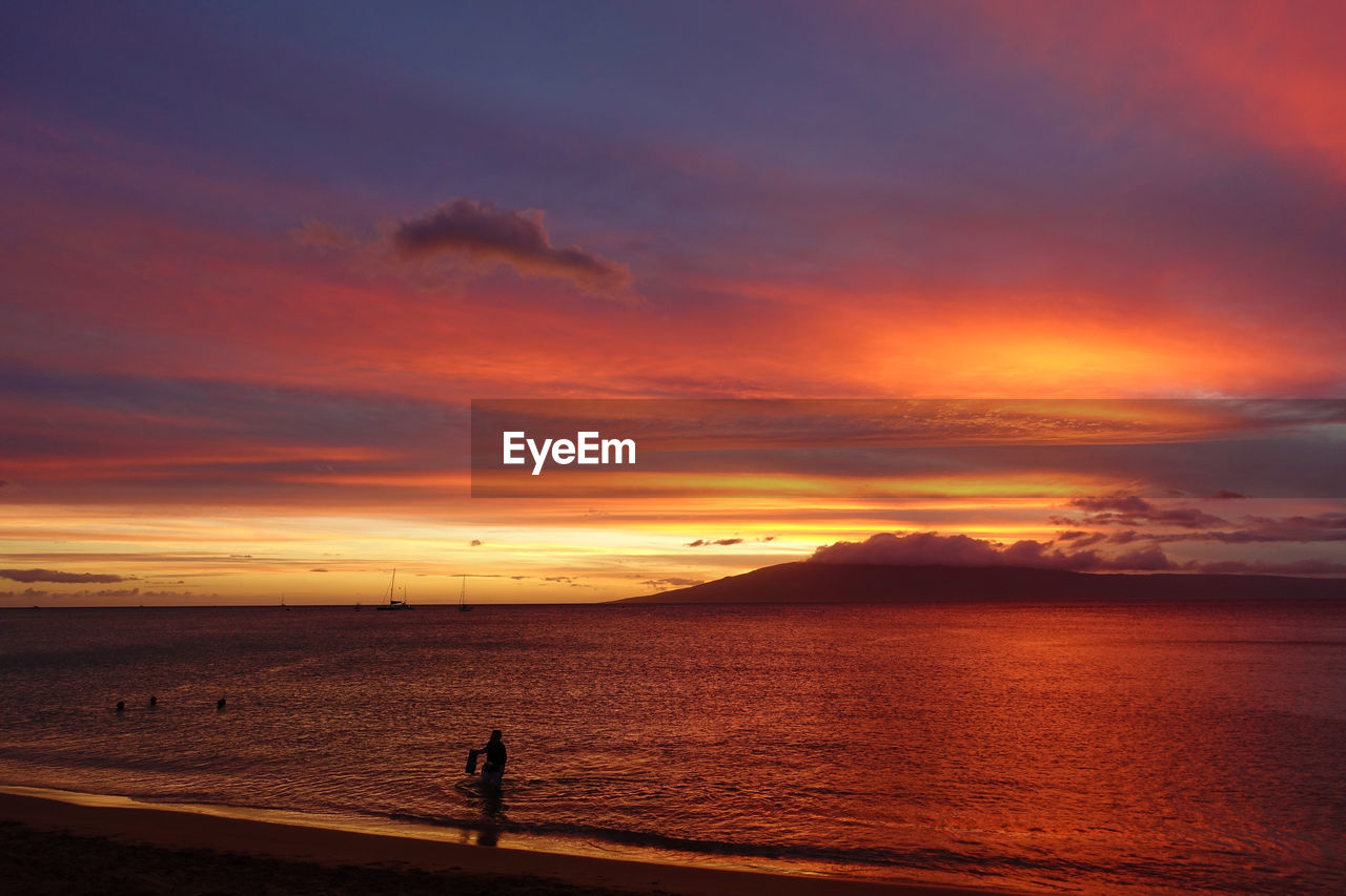 SILHOUETTE MAN ON BEACH AGAINST SKY AT SUNSET