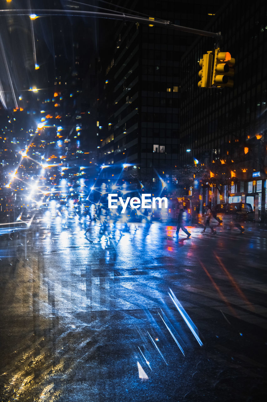 People on illuminated street in city at night