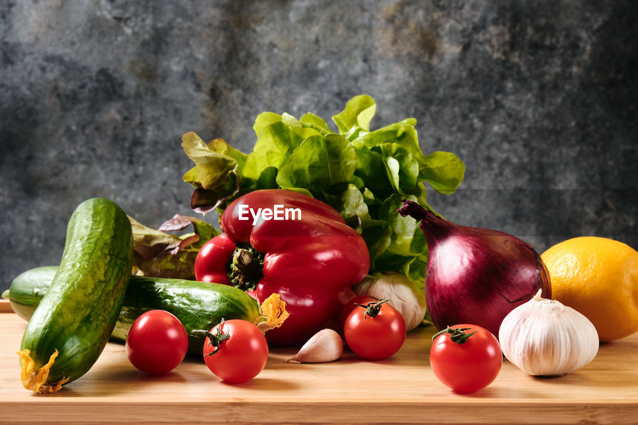 Cucumber, tomatoes, peppers, garlic and lettuce on a dark background