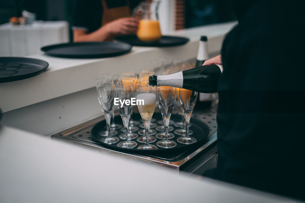 MIDSECTION OF PERSON HOLDING WINE GLASS ON TABLE AT HOME