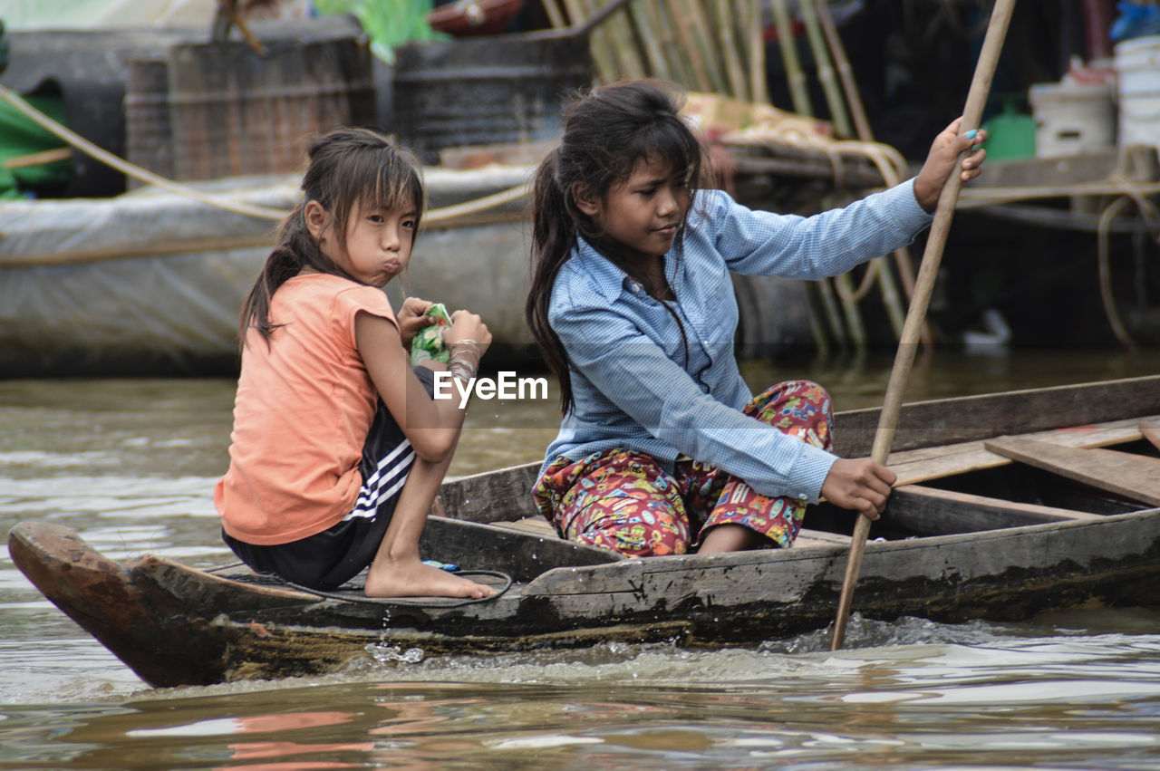 FRIENDS SITTING ON BOAT IN RIVER