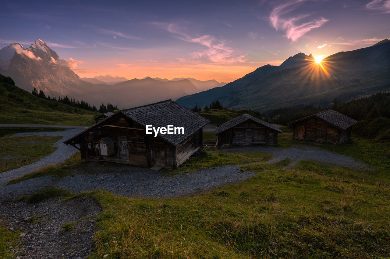 Houses on field against sky during sunset