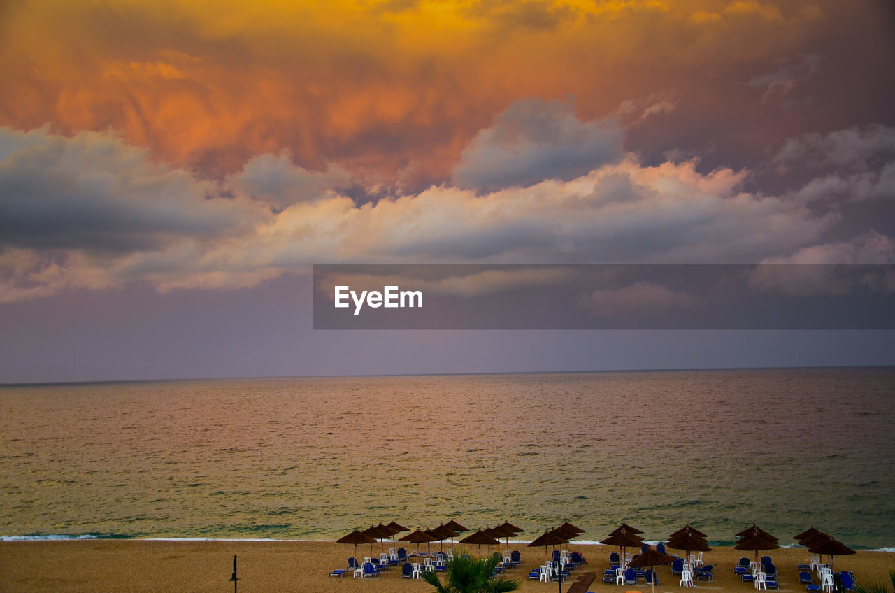 Scenic view of beach against cloudy sky during sunset