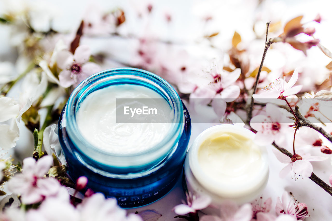 Cosmetic cream and concealer eyes creams with pink cherry flowers. skincare lotion products