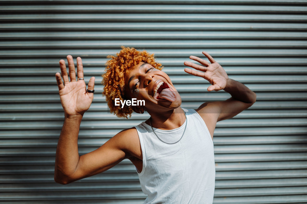 Stylish teenager with curly hair and makeup dancing hip-hop on the street