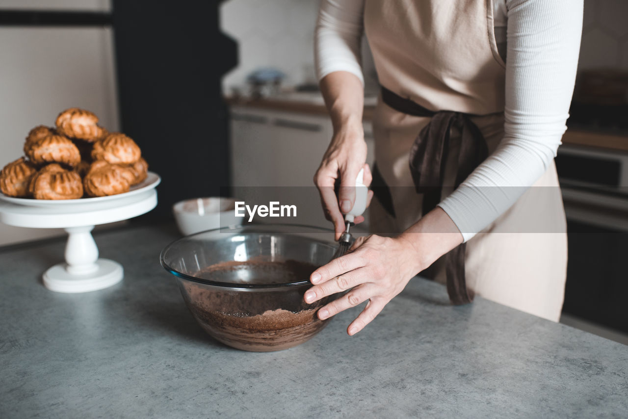 Woman making batter for chocolate cake on kithen table close up. motherhood. breakfast time.