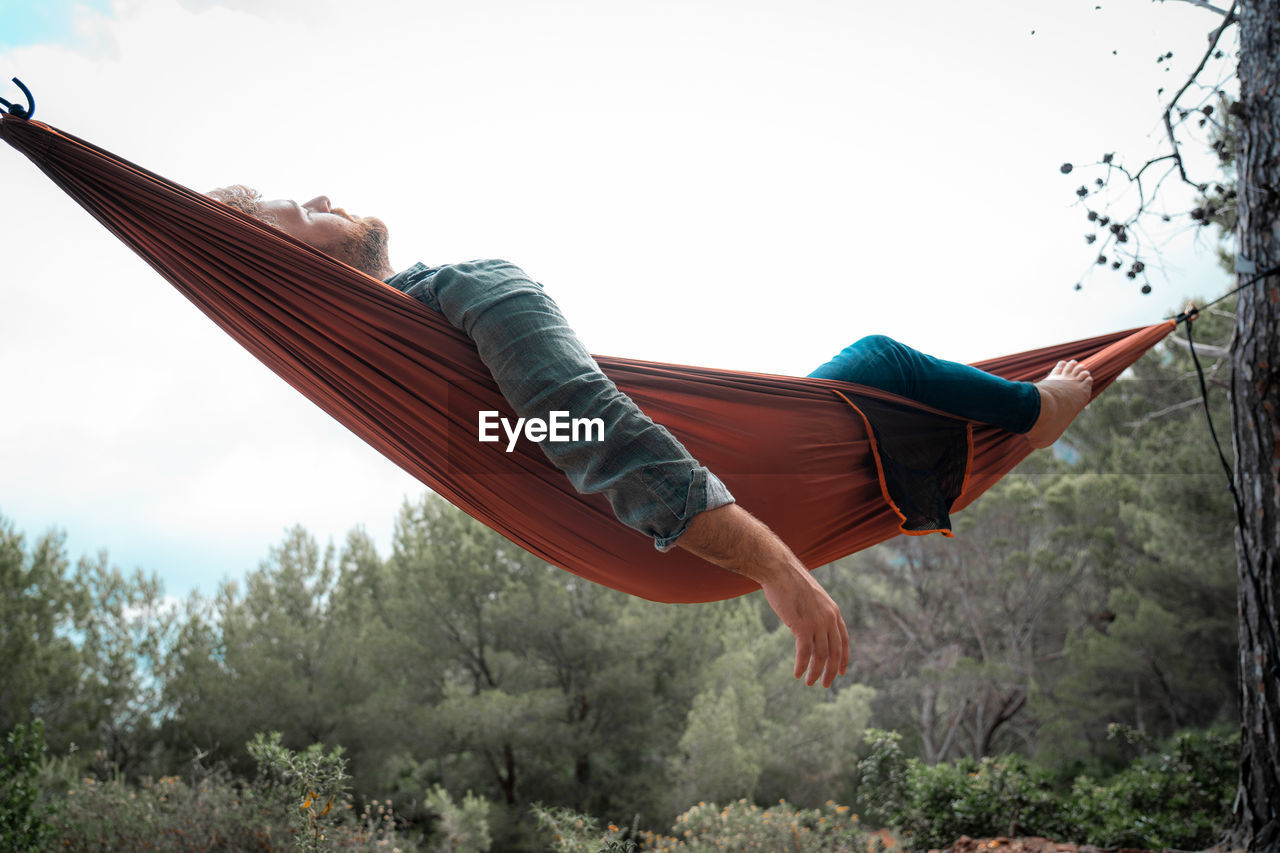 Low angle view of man lying on hammock