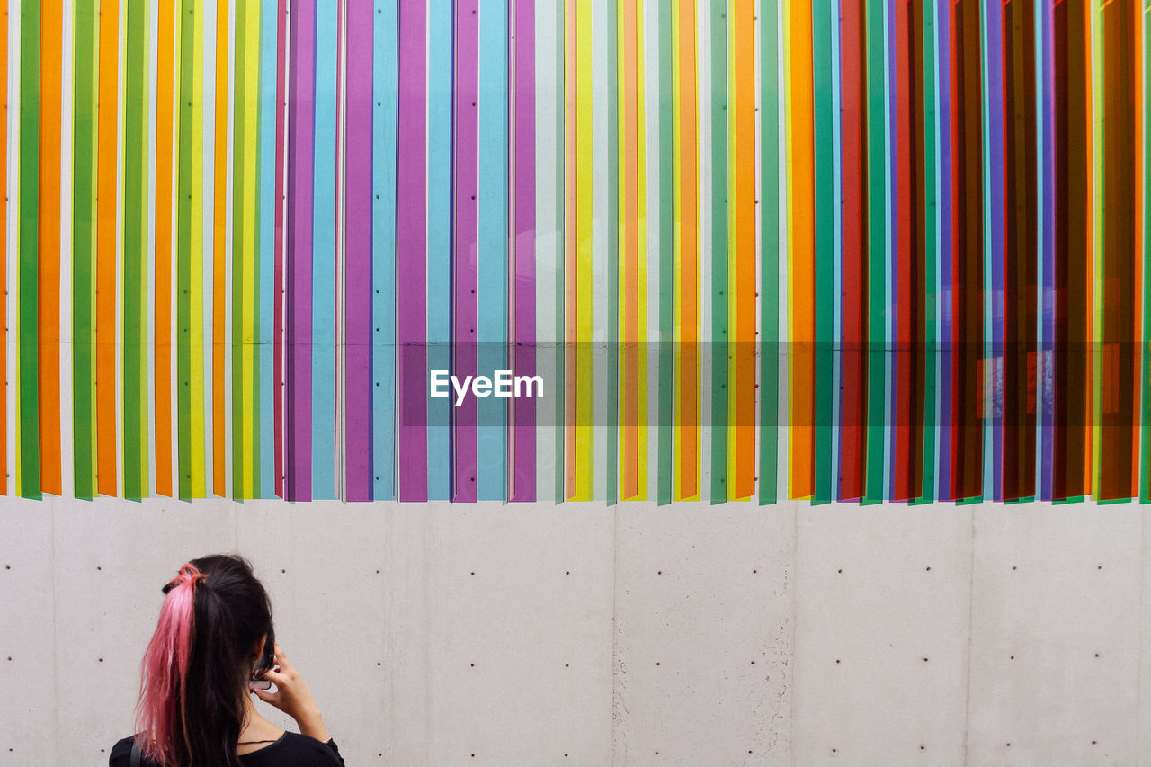 Rear view of woman looking at colorful patterned wall