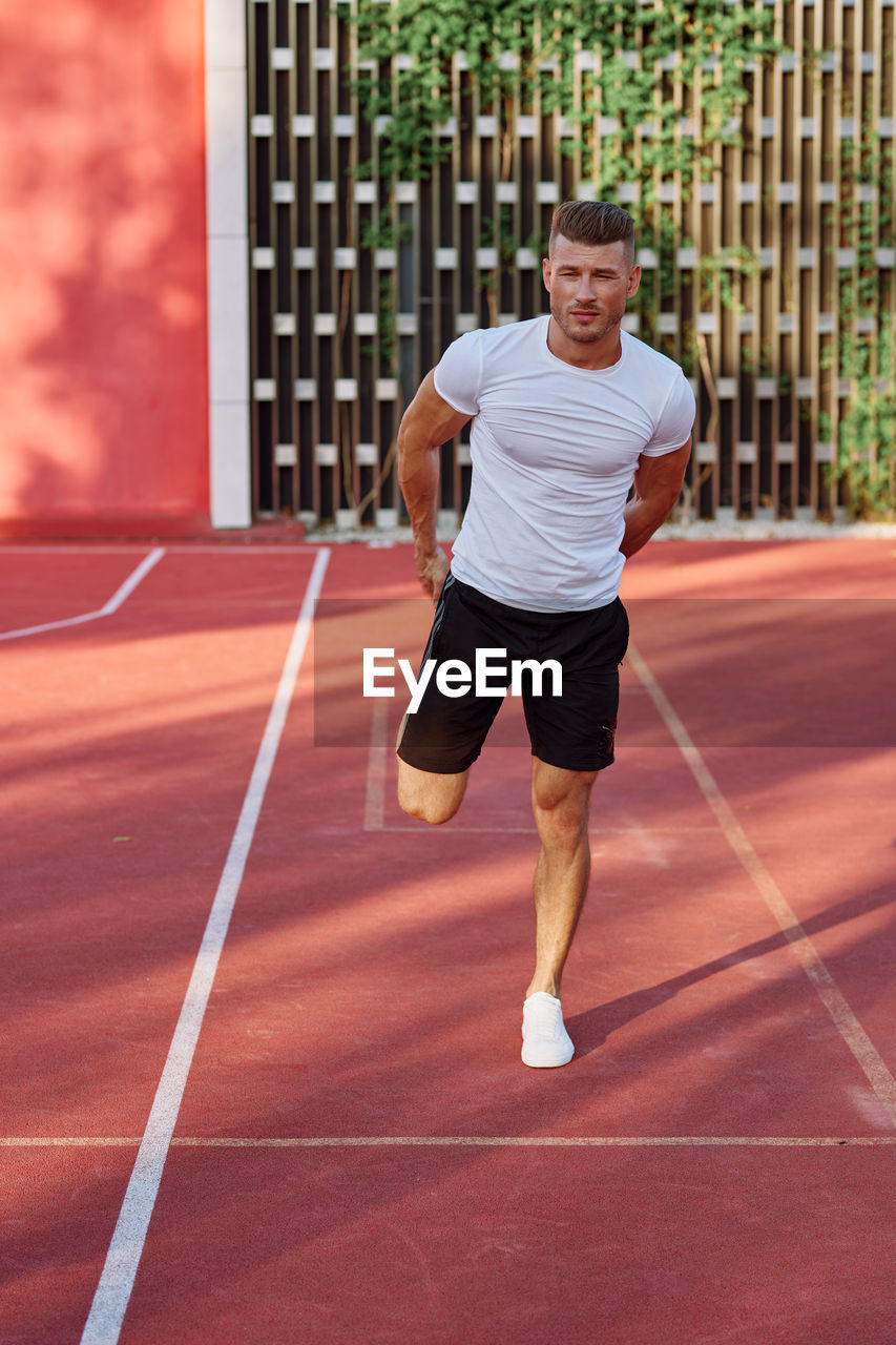 full length of young man playing tennis at court