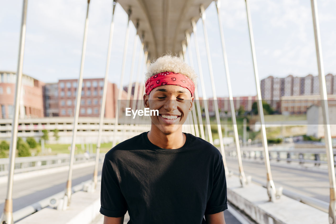 Handsome black boy with headscarf standing in the middle of the bridge