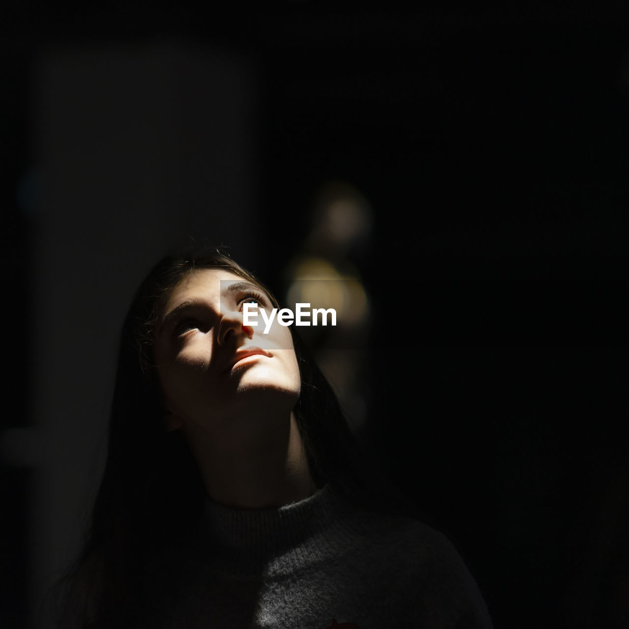 Close-up of woman looking up in dark room