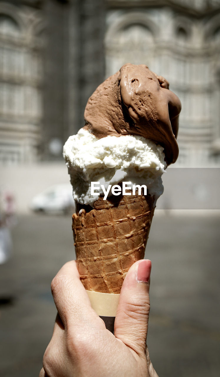 Close-up of woman hand holding ice cream cone in city