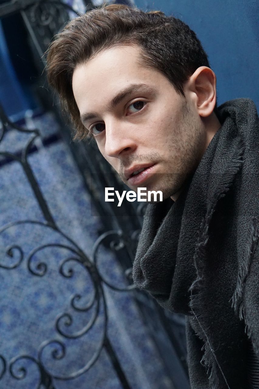 Portrait of young man wearing warm clothing standing against wall