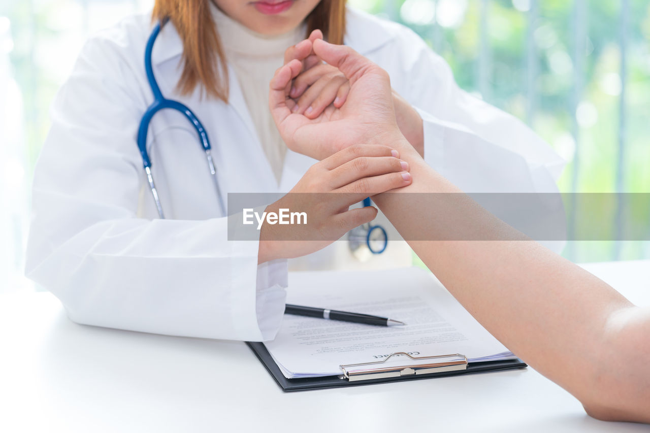 Midsection of doctor examining patient on table in hospital