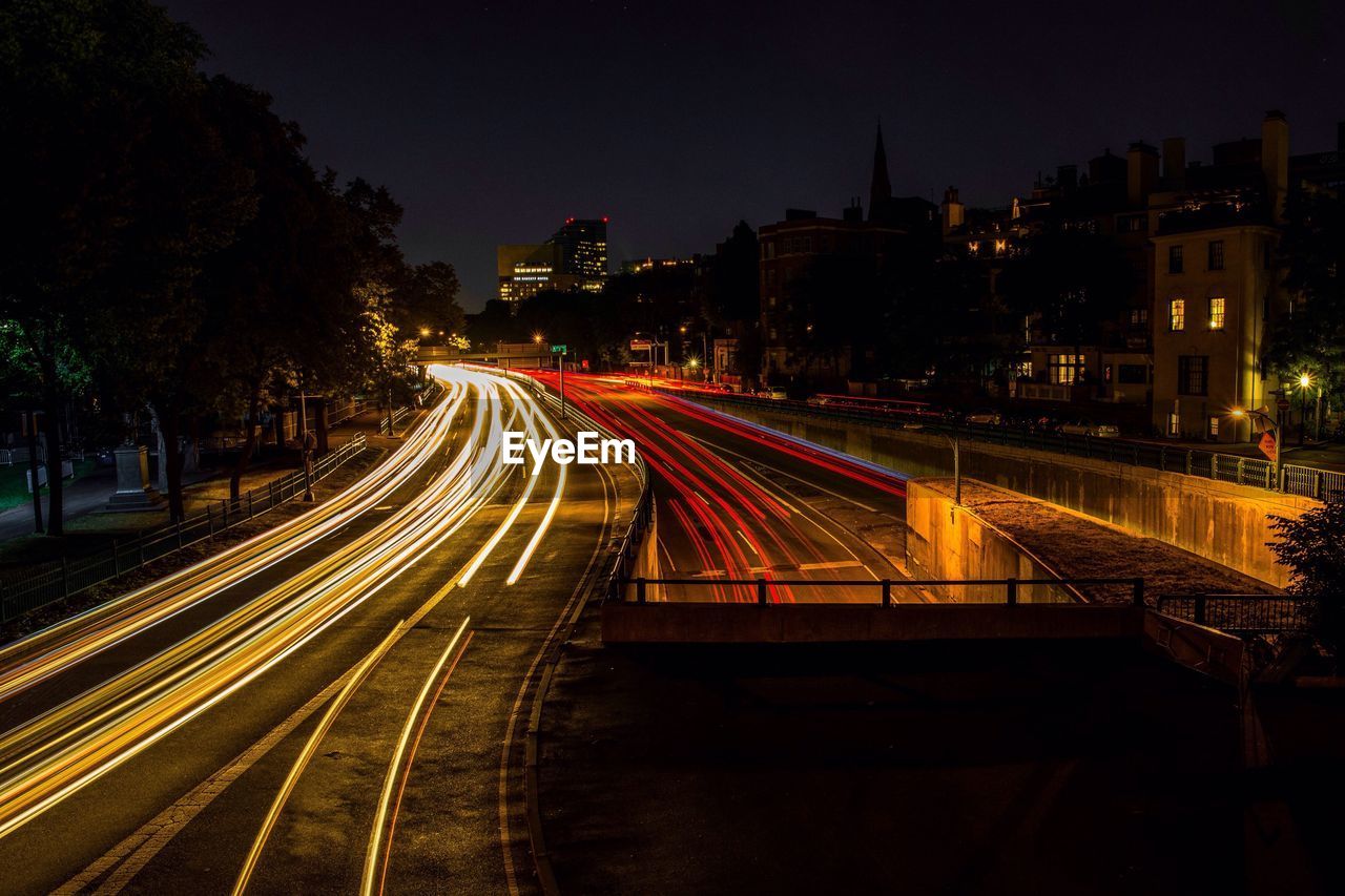 Light trails on road along buildings at night