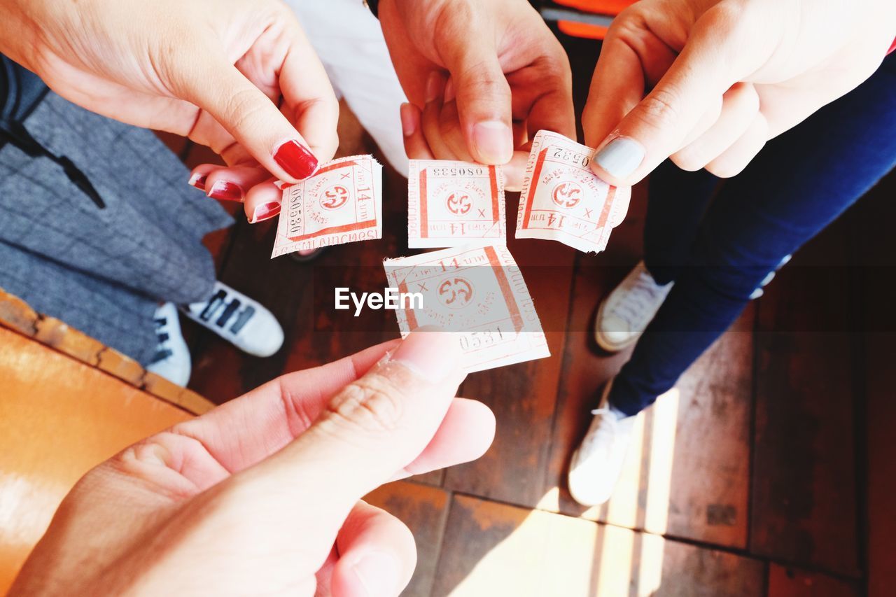 Low section of friends holding tickets on hardwood floor in ferry