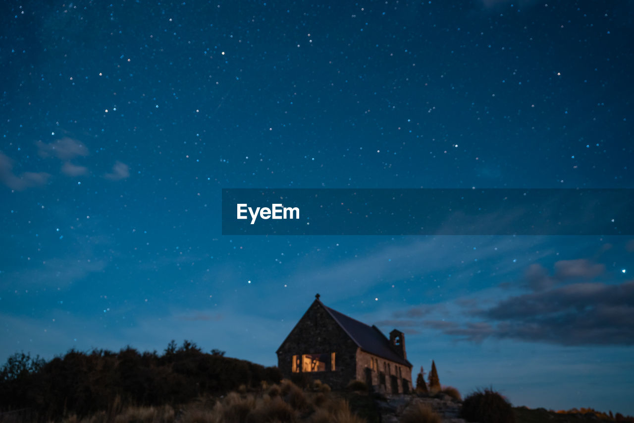 BUILDING AGAINST STAR FIELD AGAINST SKY AT NIGHT