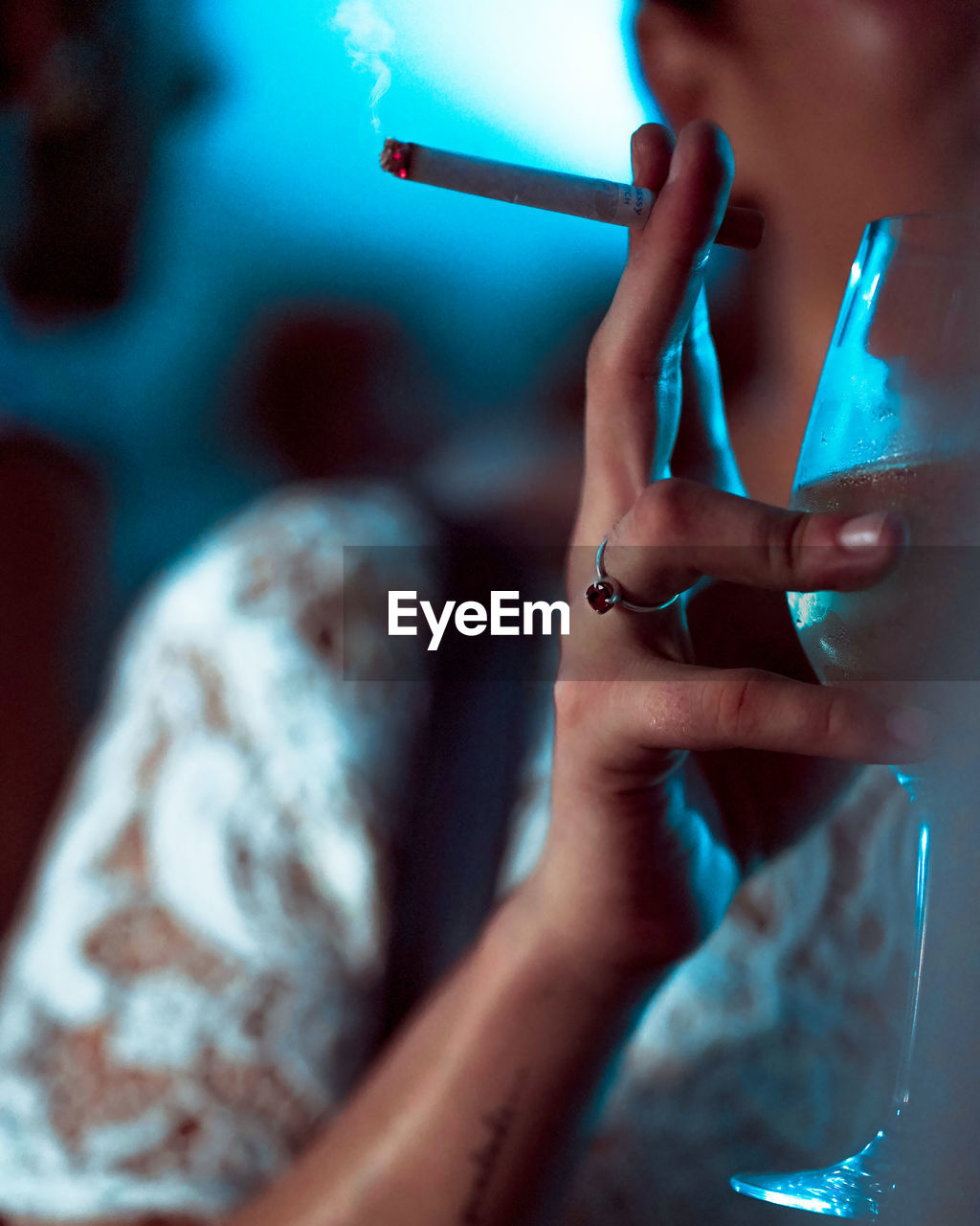 CLOSE-UP OF WOMAN HAND HOLDING CIGARETTE AGAINST BLURRED BACKGROUND