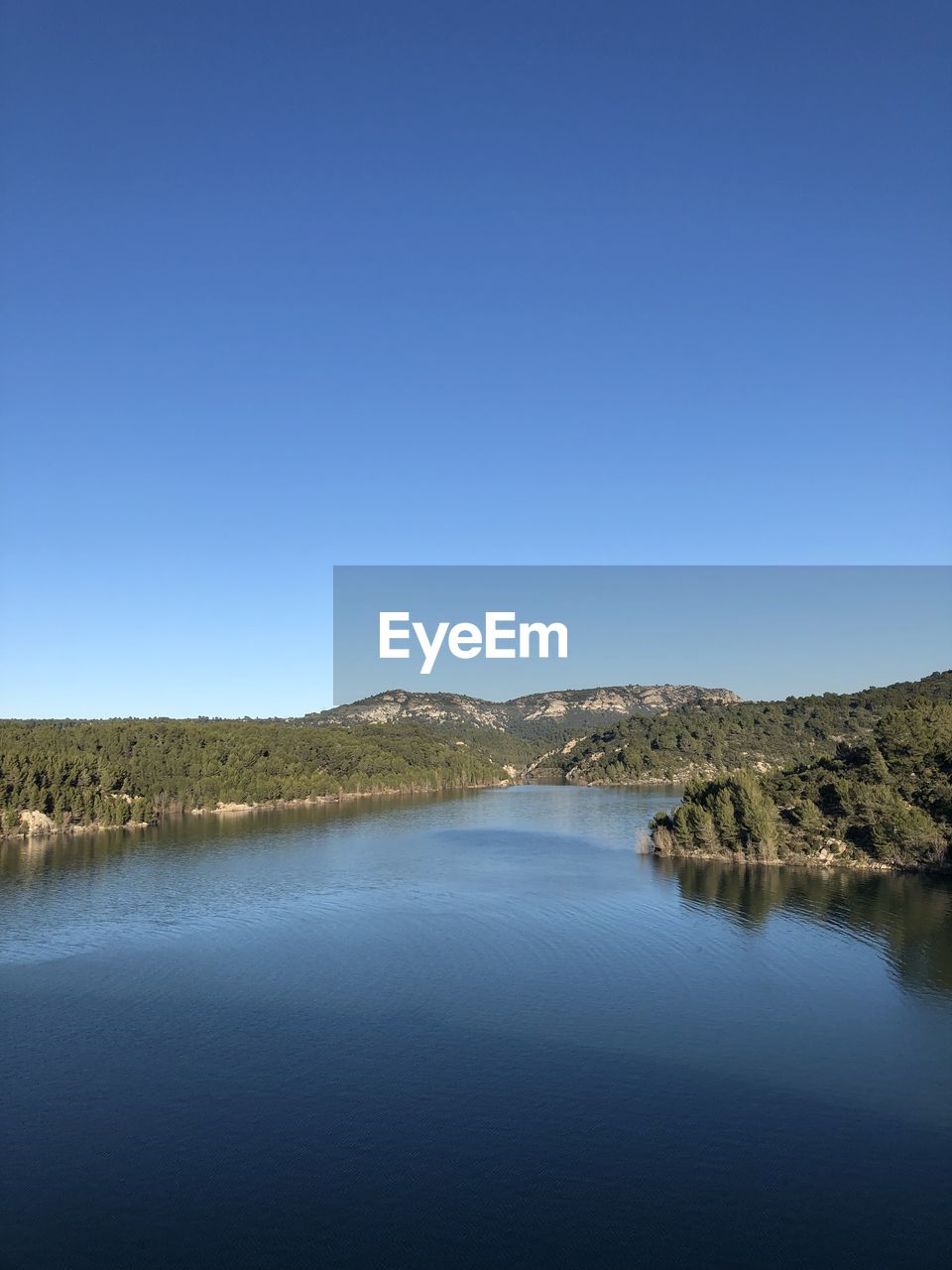 Scenic view of lake against clear blue sky