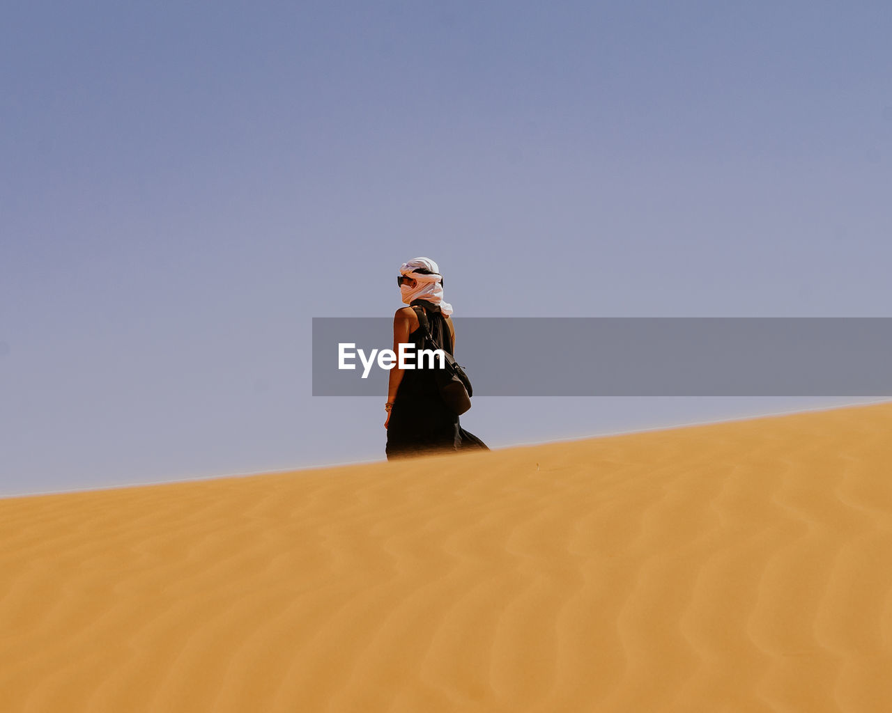 LOW ANGLE VIEW OF MAN STANDING ON SAND AGAINST CLEAR SKY