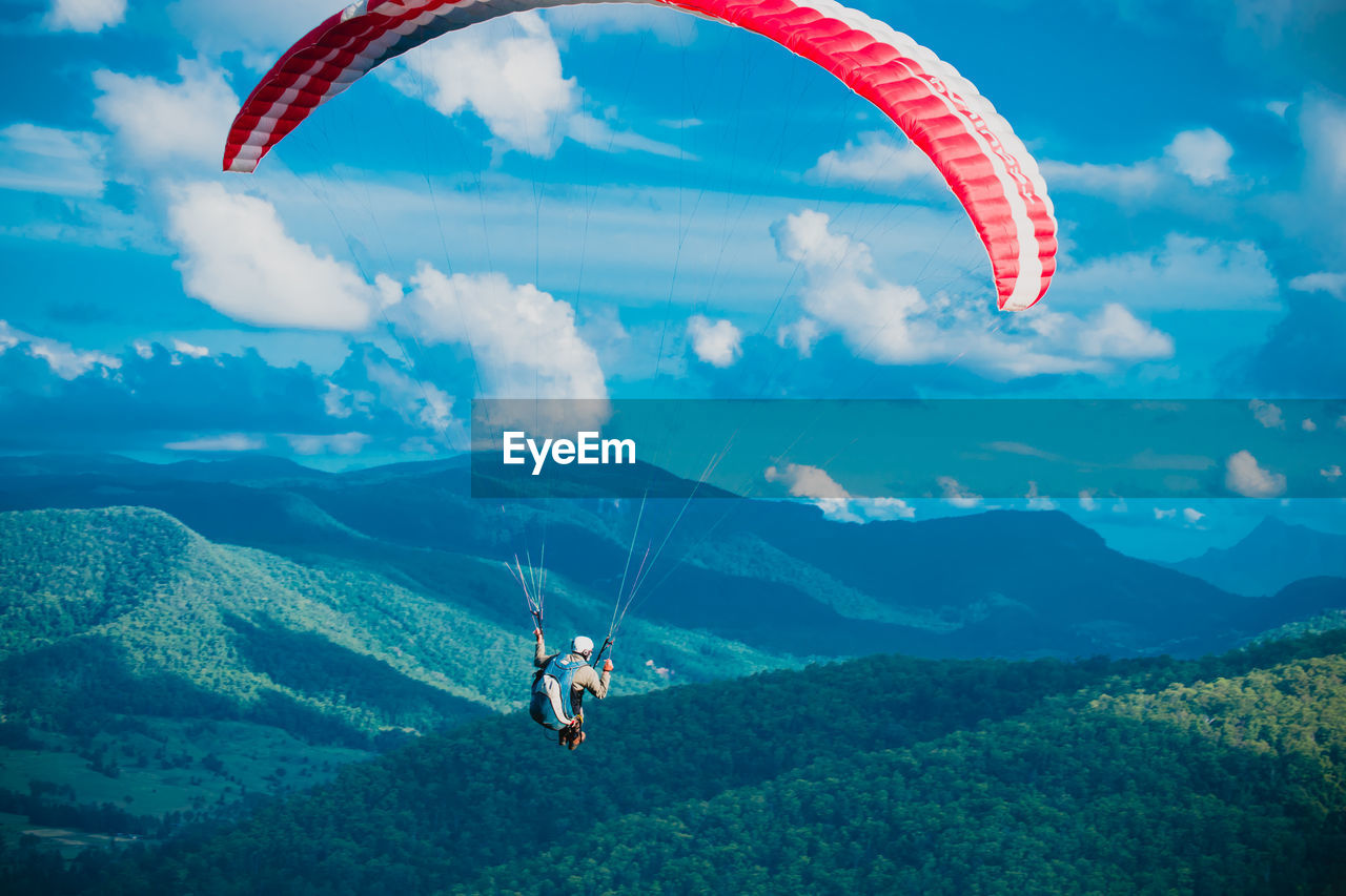 PEOPLE PARAGLIDING OVER MOUNTAINS AGAINST SKY