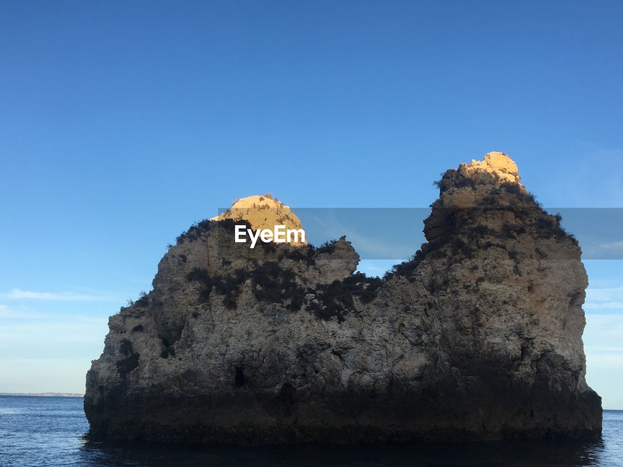 ROCK FORMATION BY SEA AGAINST CLEAR SKY