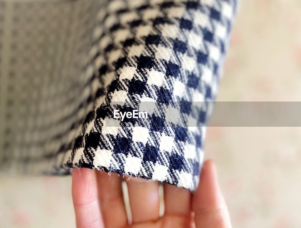 Cropped hand of woman holding houndstooth outfit