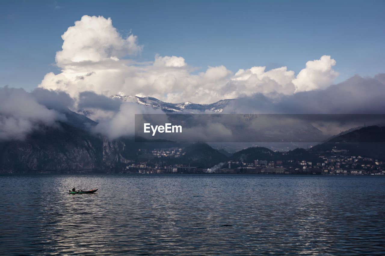 Clouds covering mountains by lake