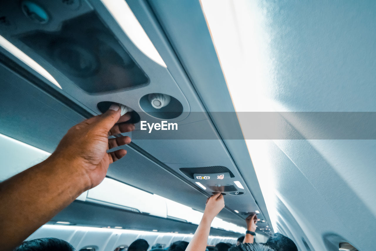 Cropped hands adjusting air conditioner in airplane