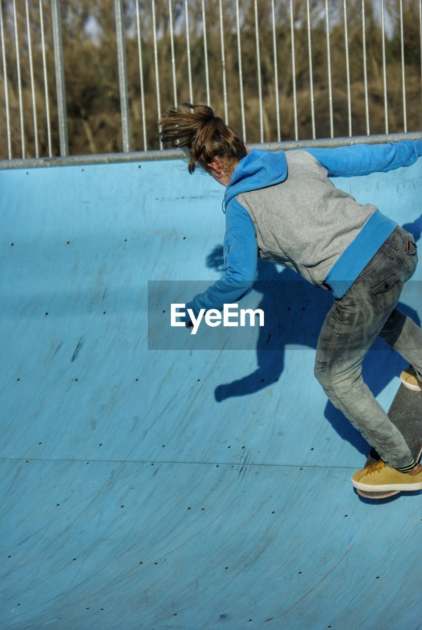 Full length rear view of woman skateboarding on sports ramp