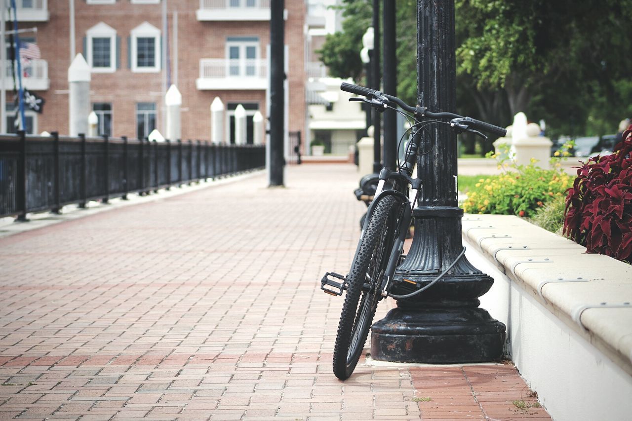 Bicycle parked by pole on footpath