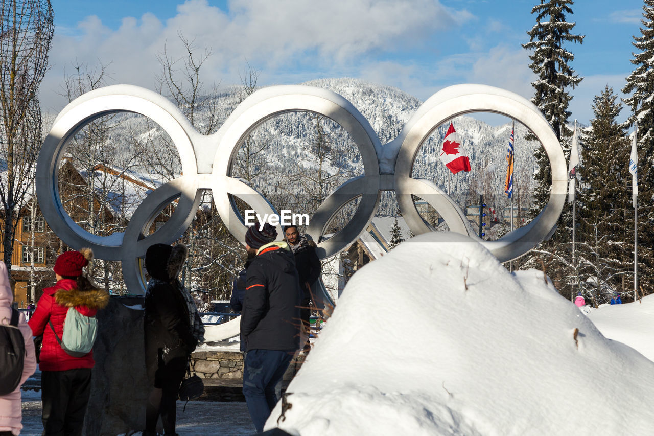 REAR VIEW OF PEOPLE WALKING ON SNOW COVERED FIELD