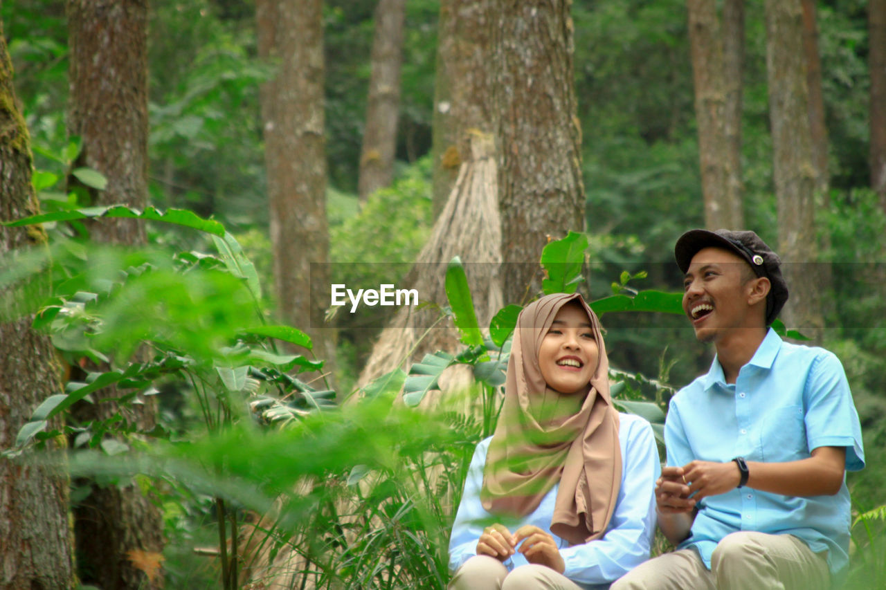 Smiling young couple sitting at forest