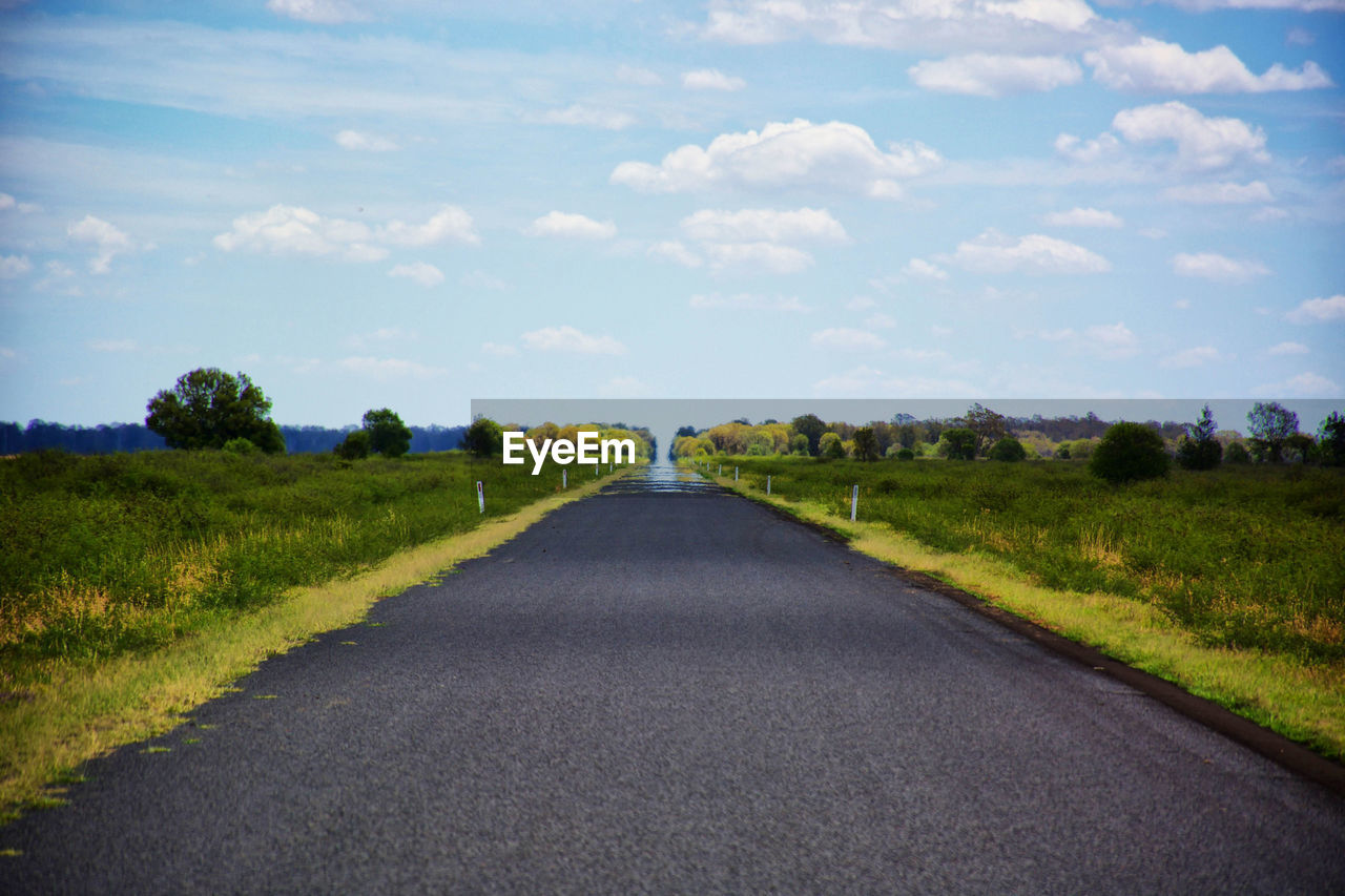 Road amidst field against sky