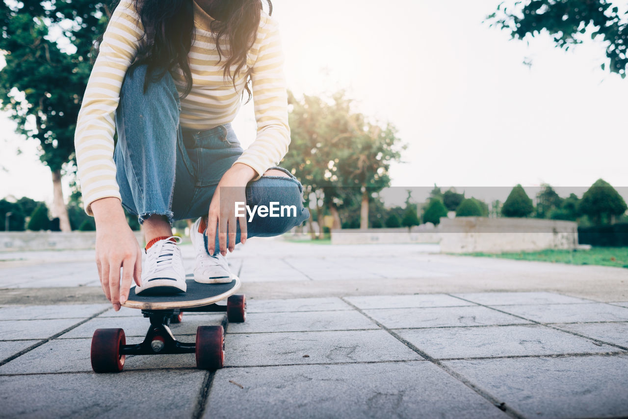 Low section of woman skateboarding on street