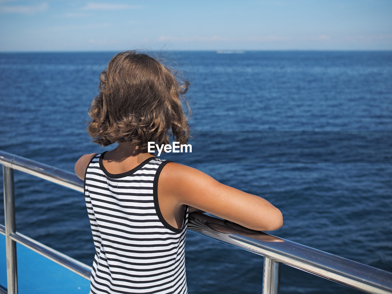 Rear view of girl in boat looking at sea against sky