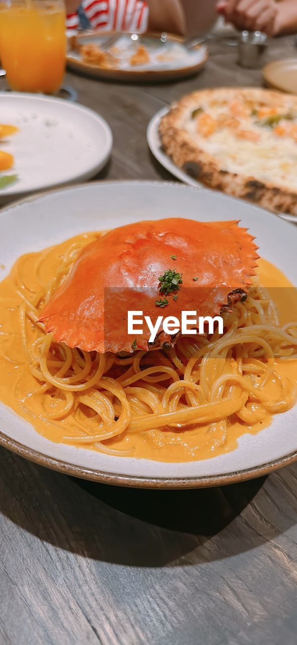 food and drink, food, plate, italian food, pasta, meal, table, freshness, dish, healthy eating, cuisine, indoors, seafood, wellbeing, spaghetti, hand, crockery, dinner, savory food, close-up, meat, vegetable, fruit, restaurant, condiment, sauce, high angle view, focus on foreground, pasta pomodoro