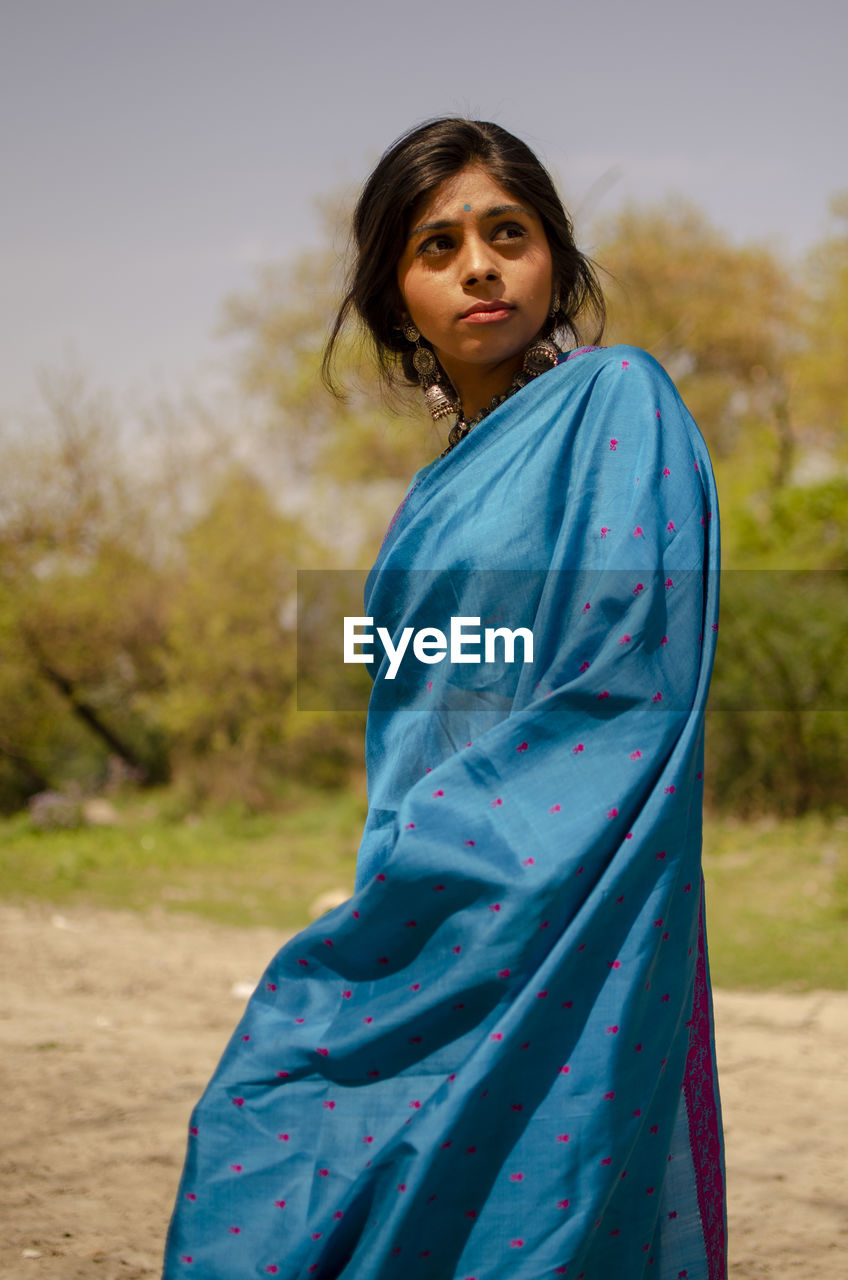 Beautiful woman wearing sari while standing against trees