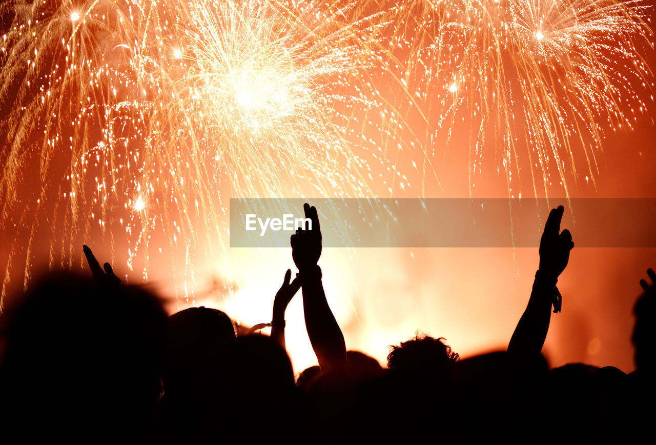 Silhouette people against firework display at night