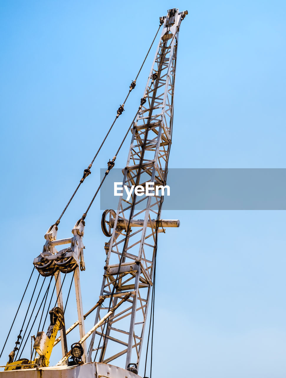 Industrial white rusty crane on blue sky