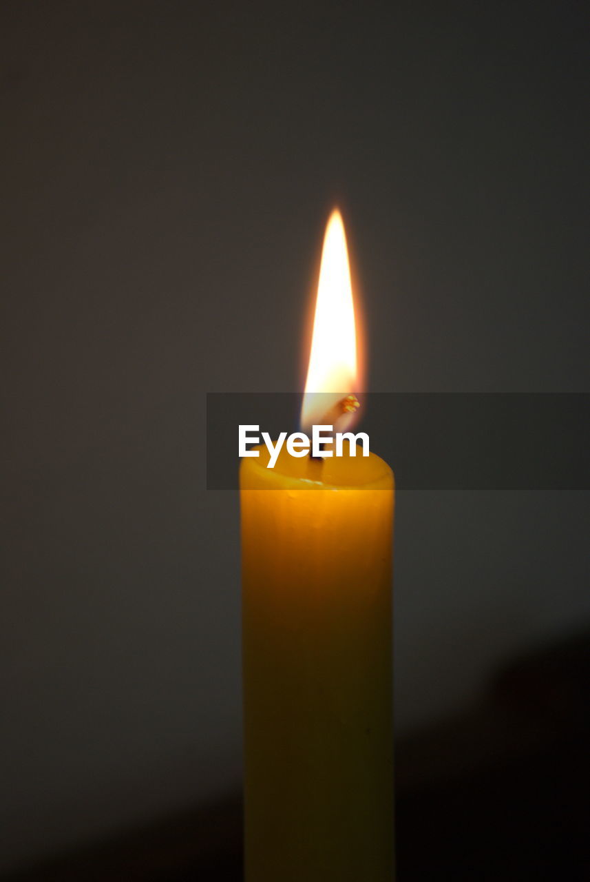 Close-up of burning candle against black background