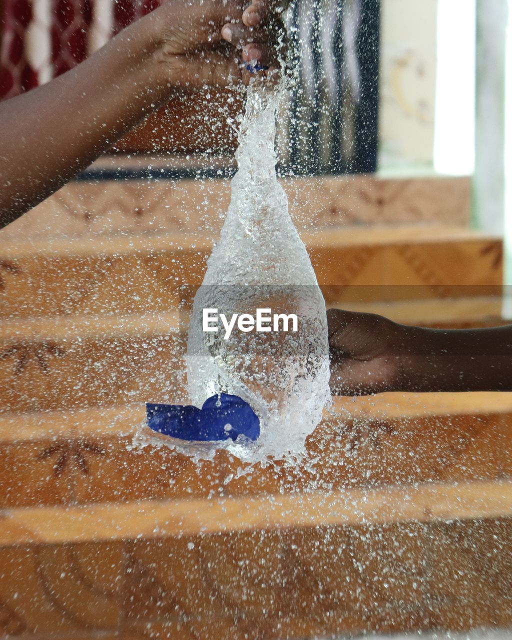 Cropped hands breaking water bomb against steps