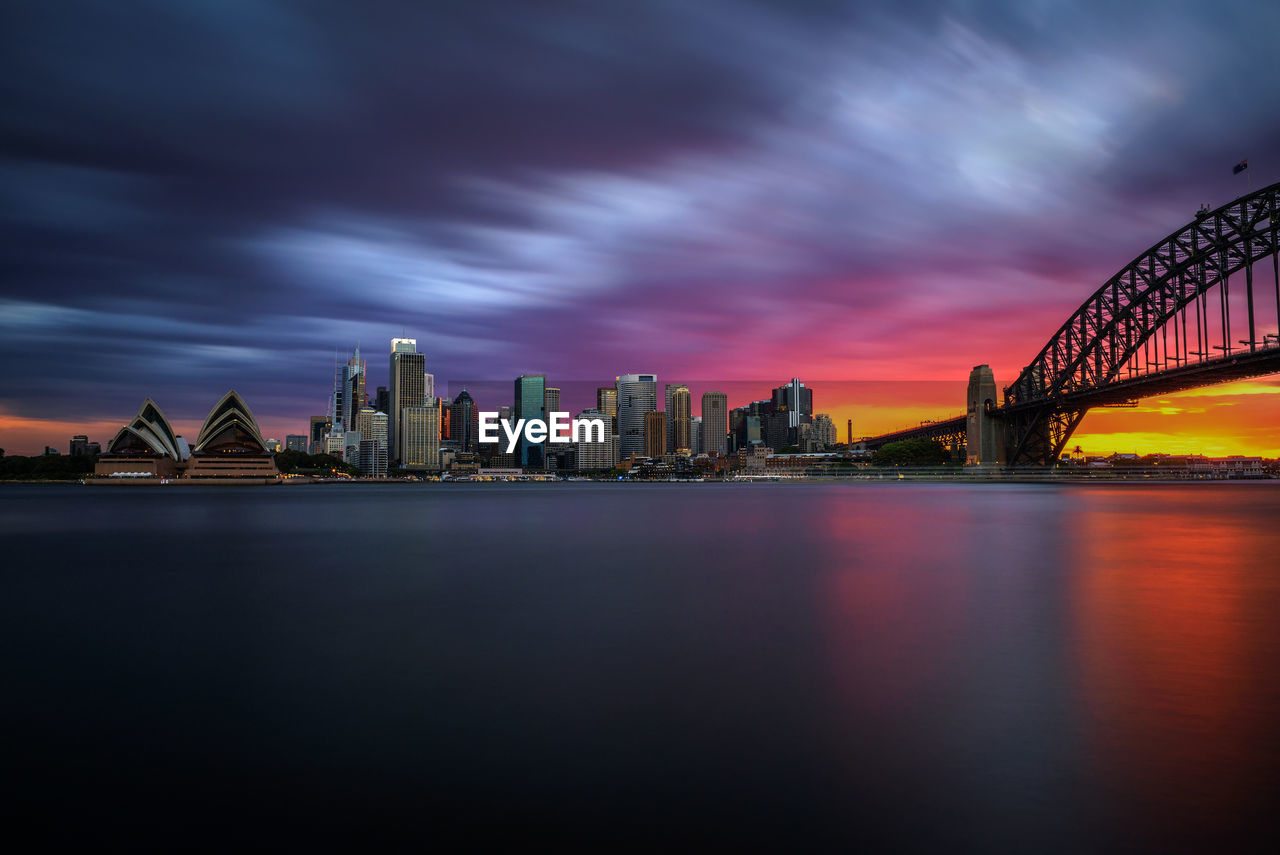 ILLUMINATED MODERN BUILDINGS IN CITY AT WATERFRONT