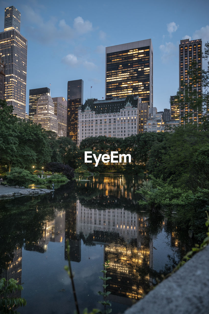 Reflection of illuminated buildings in city at night central park